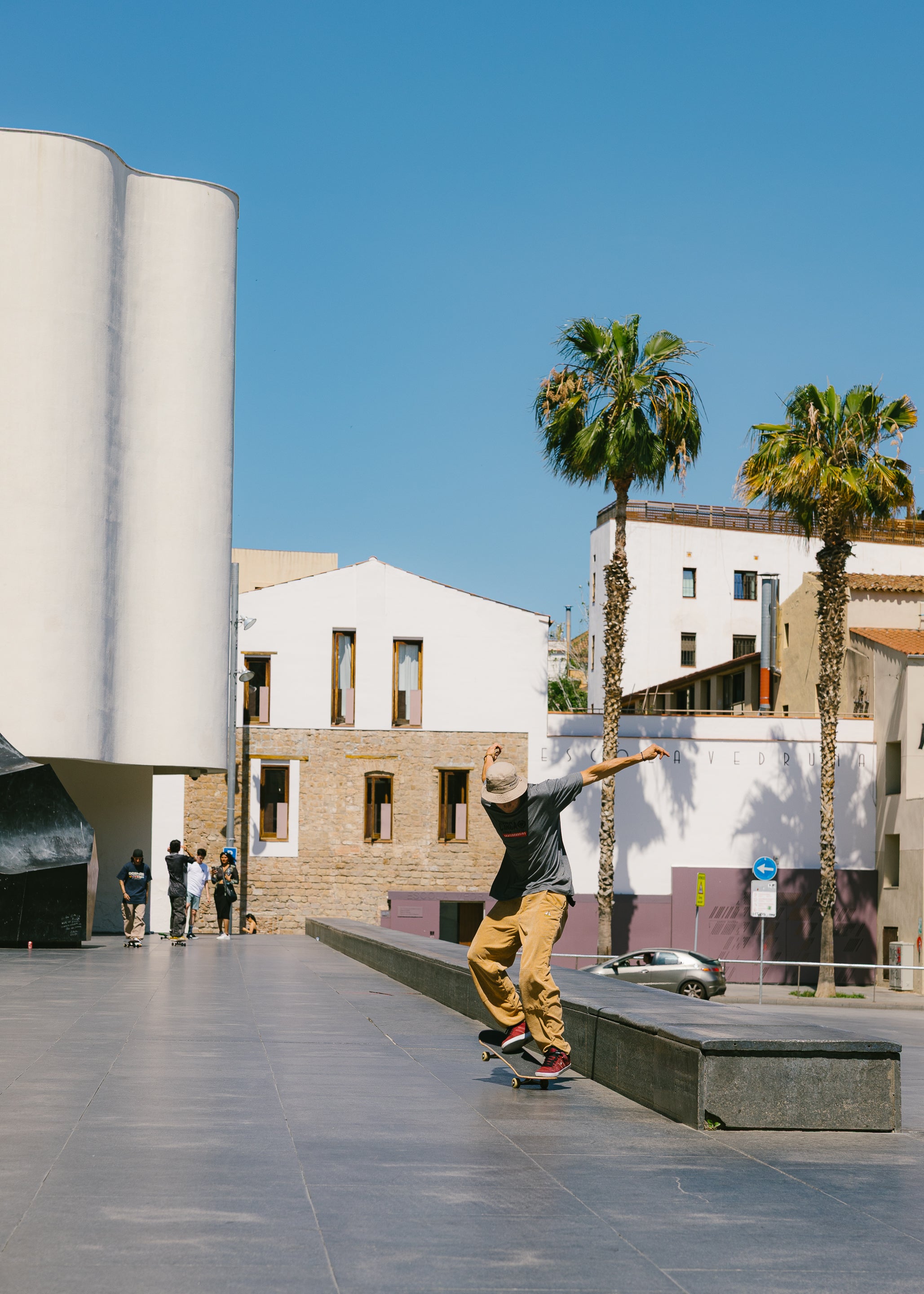 A printed photograph depicting a person skateboarding in a plaza with palm trees and buildings in the background.